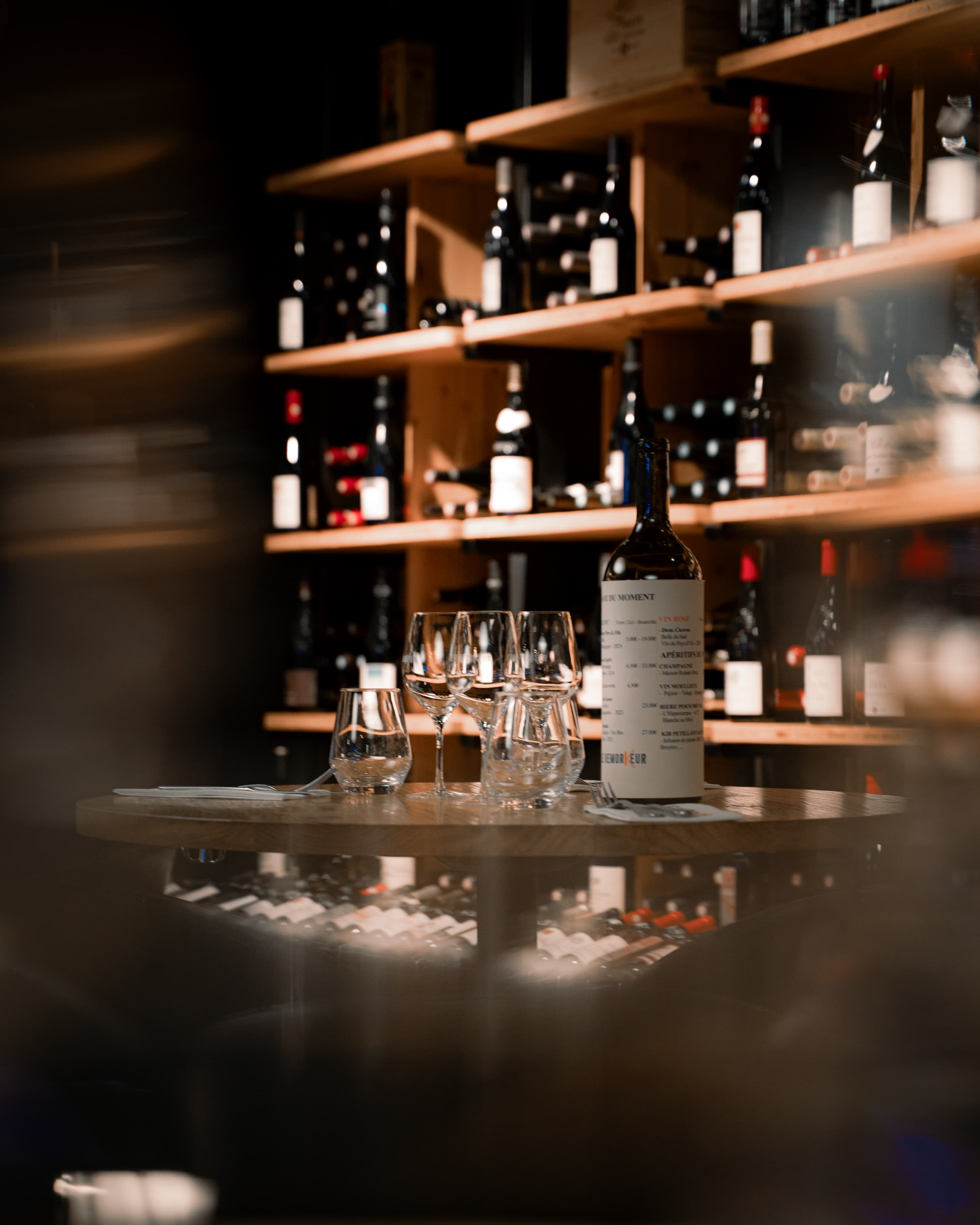 Table dressée avec bouteille et verres à vin devant la cave à vins