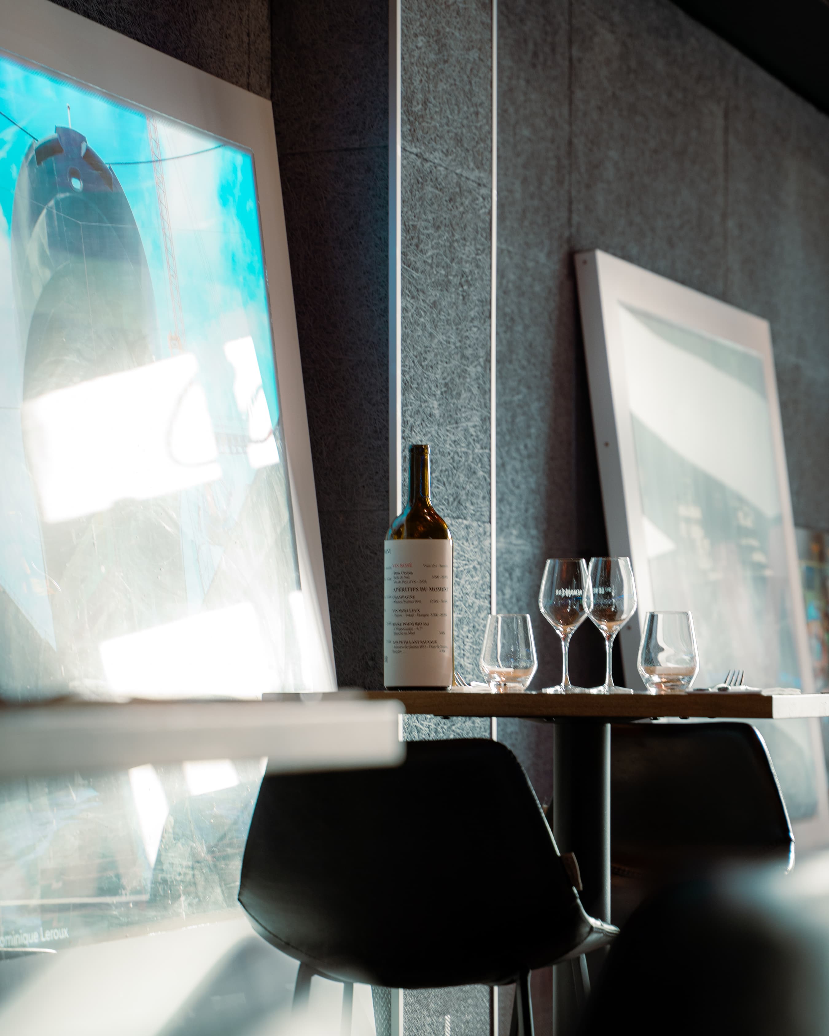Table haute avec bouteille de vin face à des photographies du port de Brest